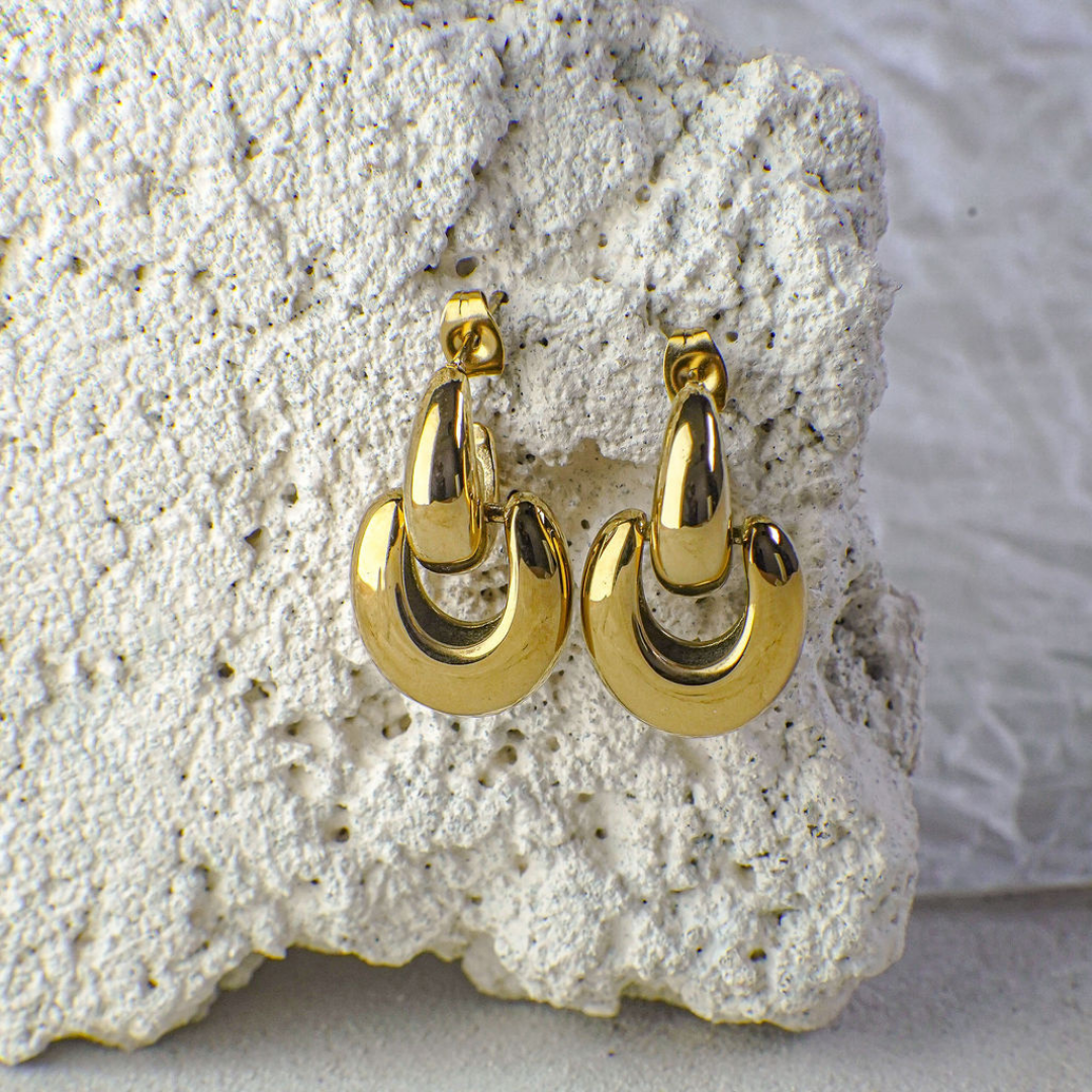 Gold hoop earrings on a textured stone surface