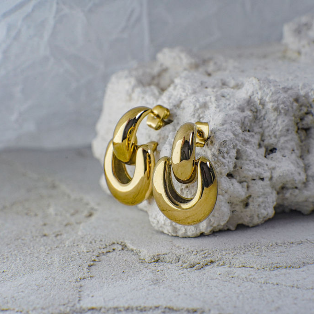 Gold hoop earrings on a textured white surface