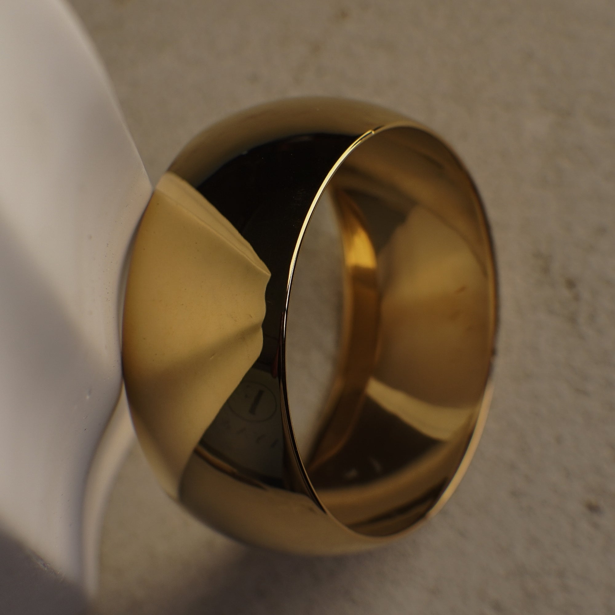 Gold bangle on a textured beige surface