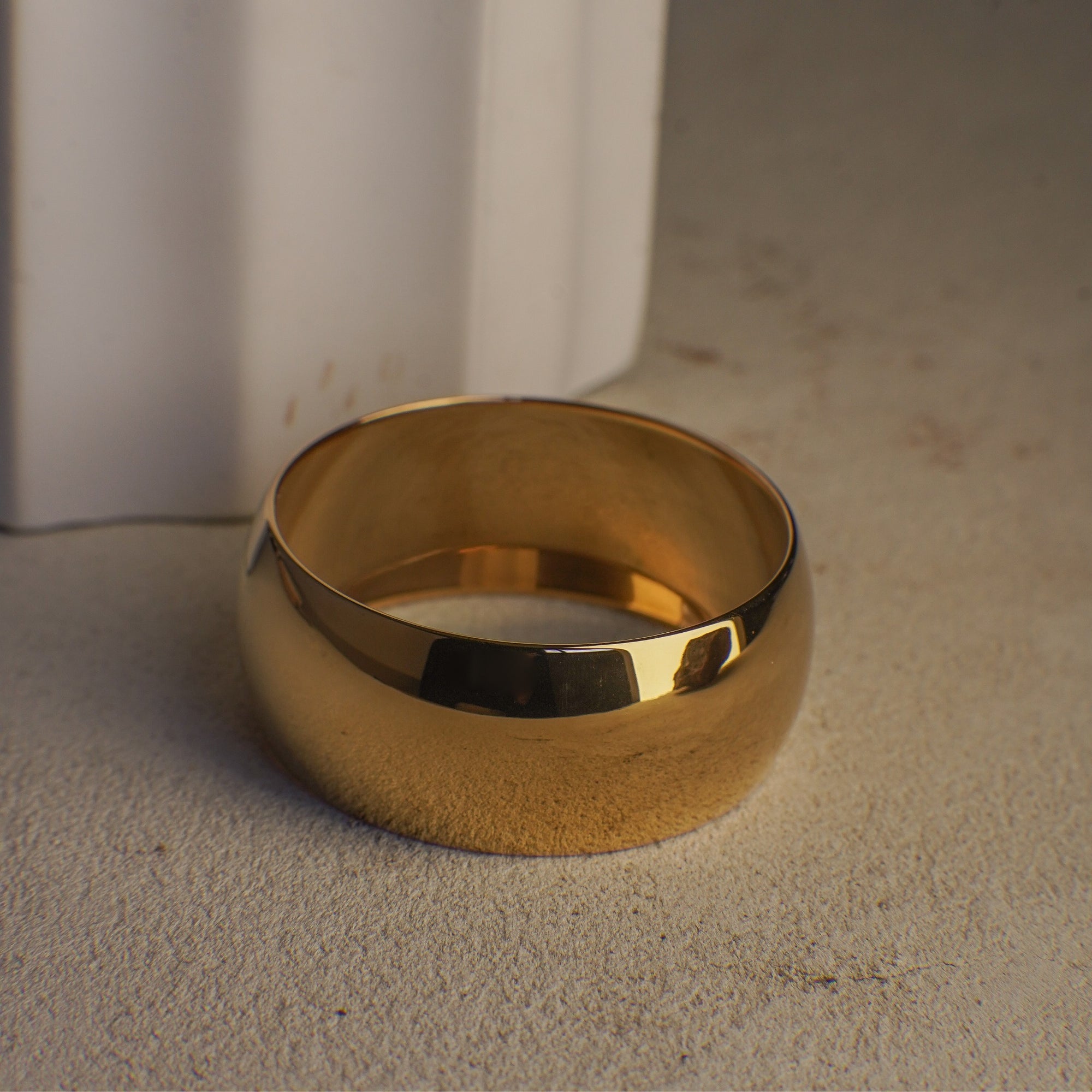 Gold bangle on a textured surface with a neutral background