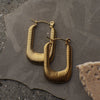 Gold hoop earrings on a textured stone surface