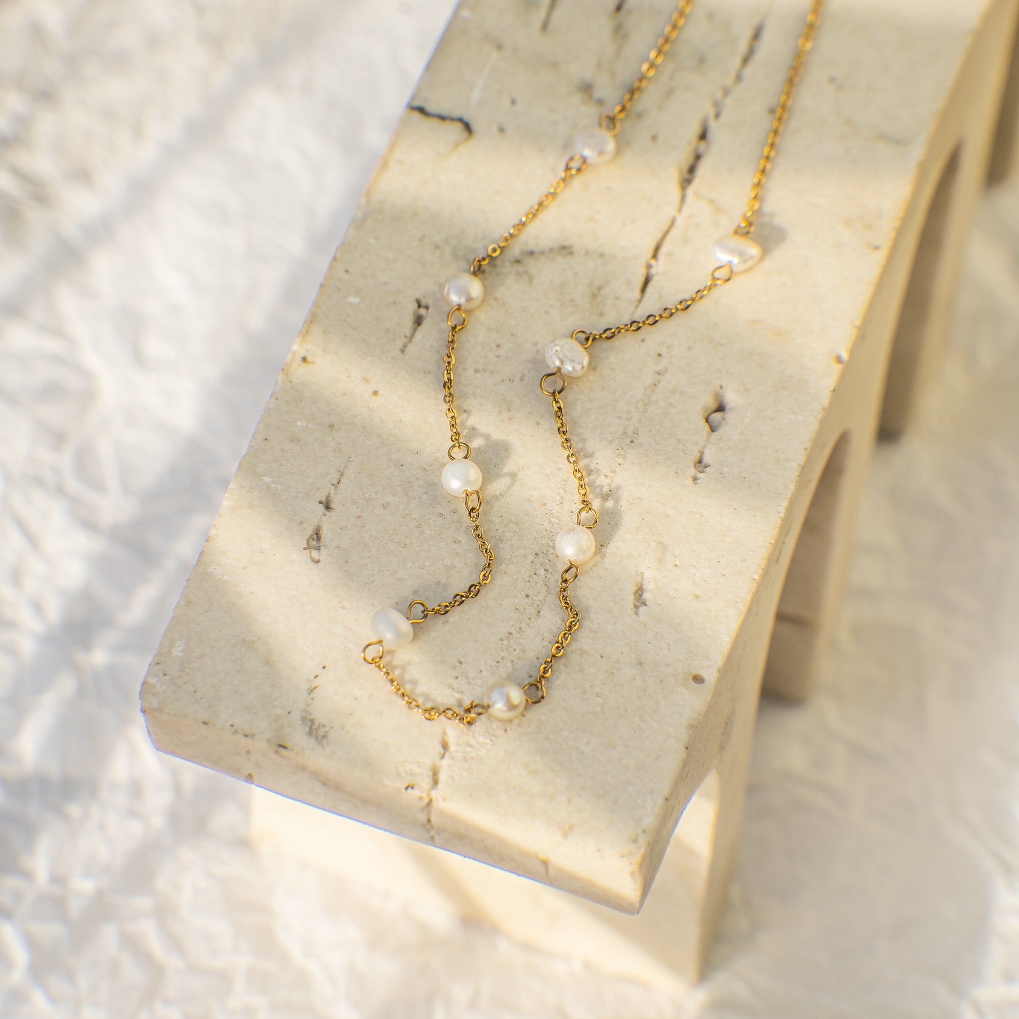 Gold necklace with pearls on a marble stand