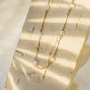 Gold necklace with pearls on a textured beige surface