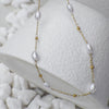 Necklace with pearls and gold beads on a white textured surface
