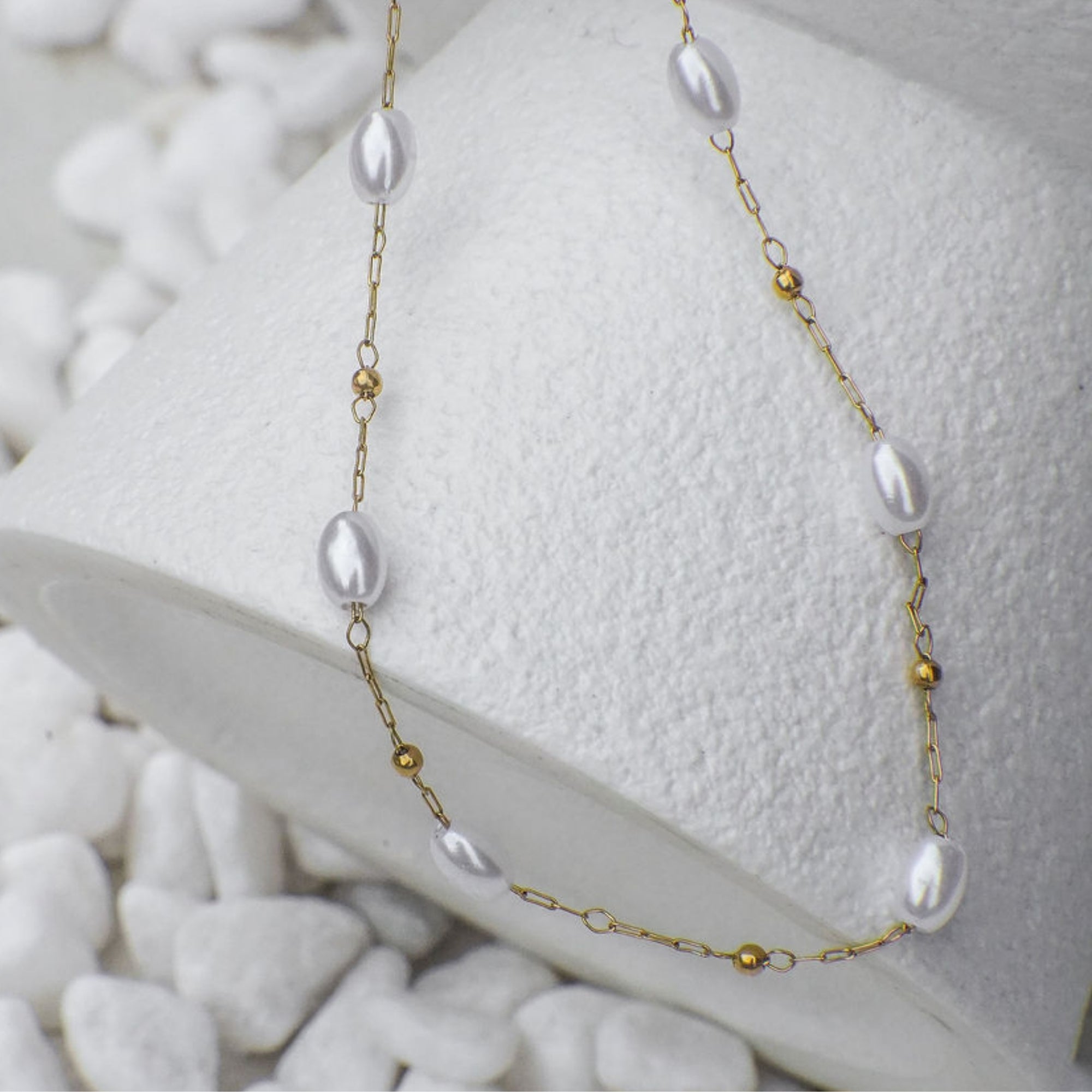 Necklace with pearls and gold beads on a white textured surface