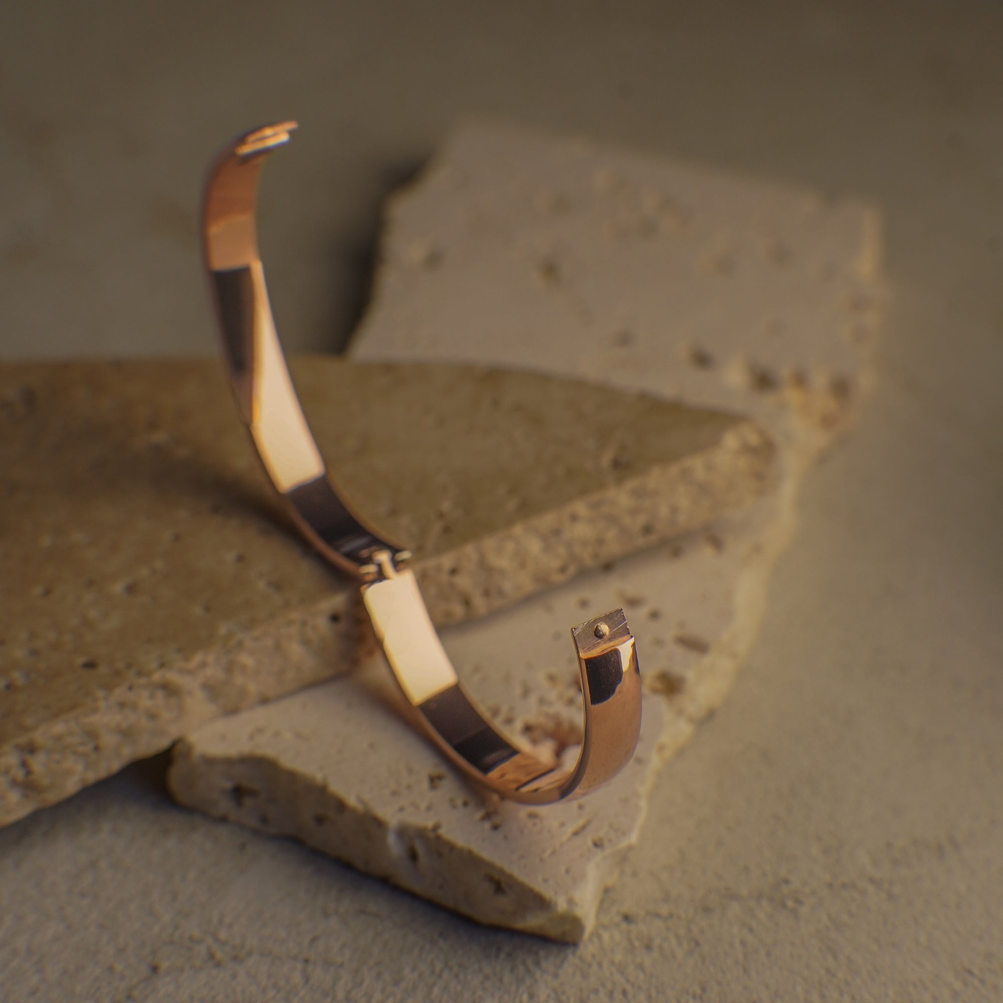 Rose gold bracelet on a textured stone surface
