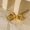 Gold earrings on a textured beige surface
