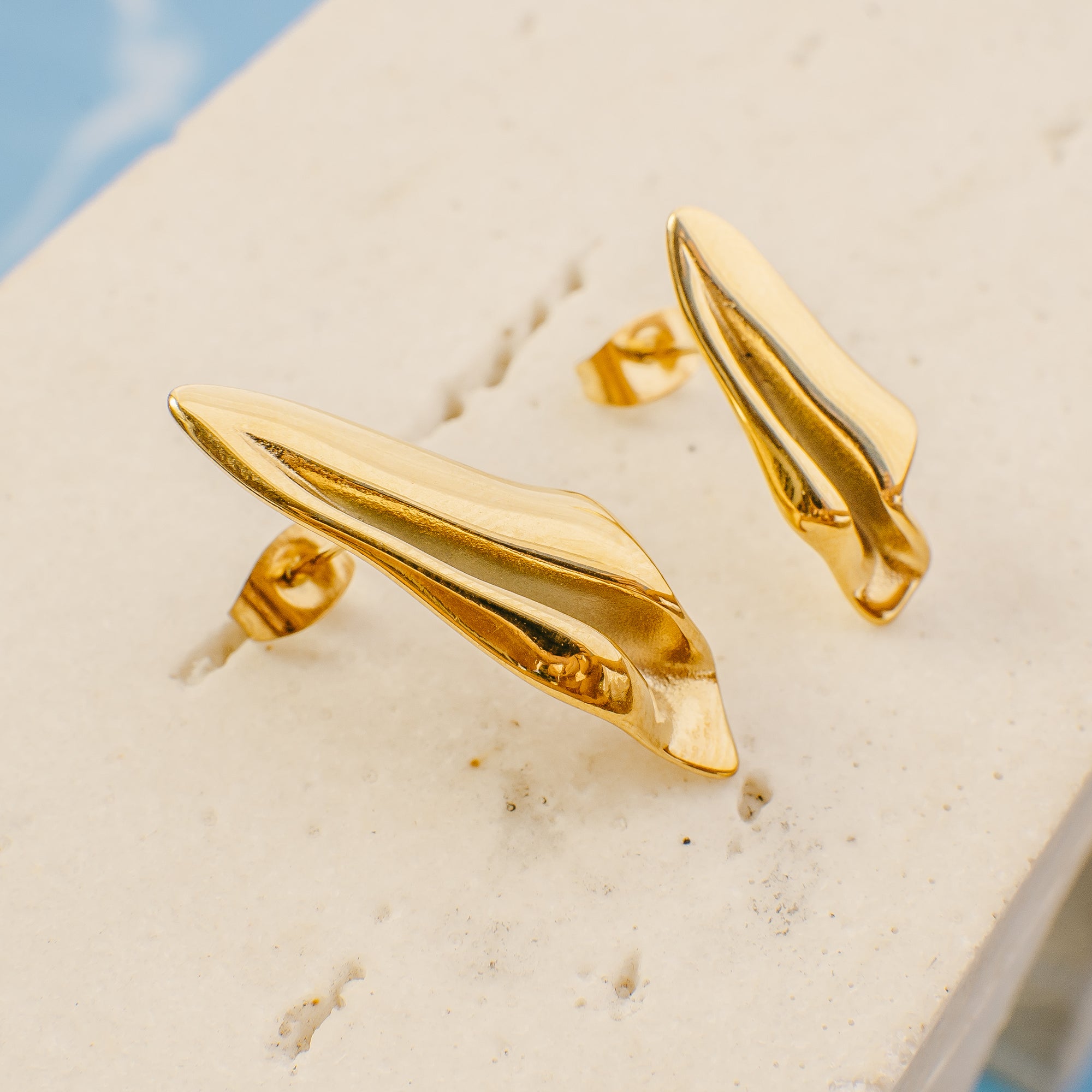 Gold earrings on a beige background