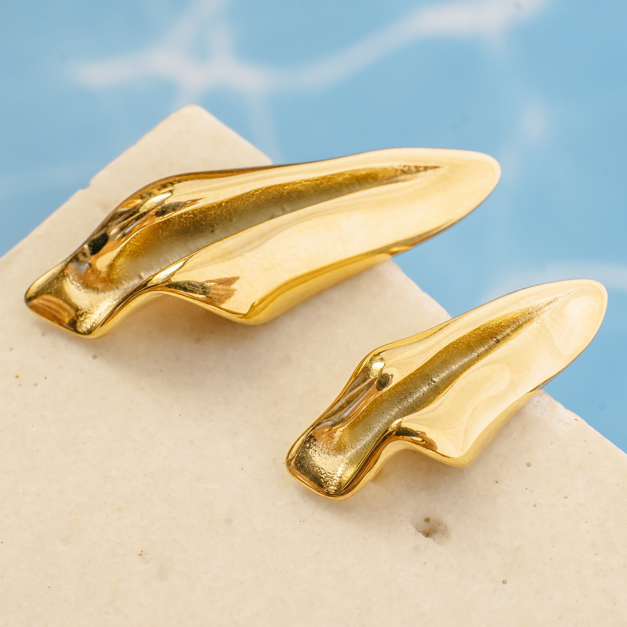 Gold shoe clips on a stone surface with a blue sky background