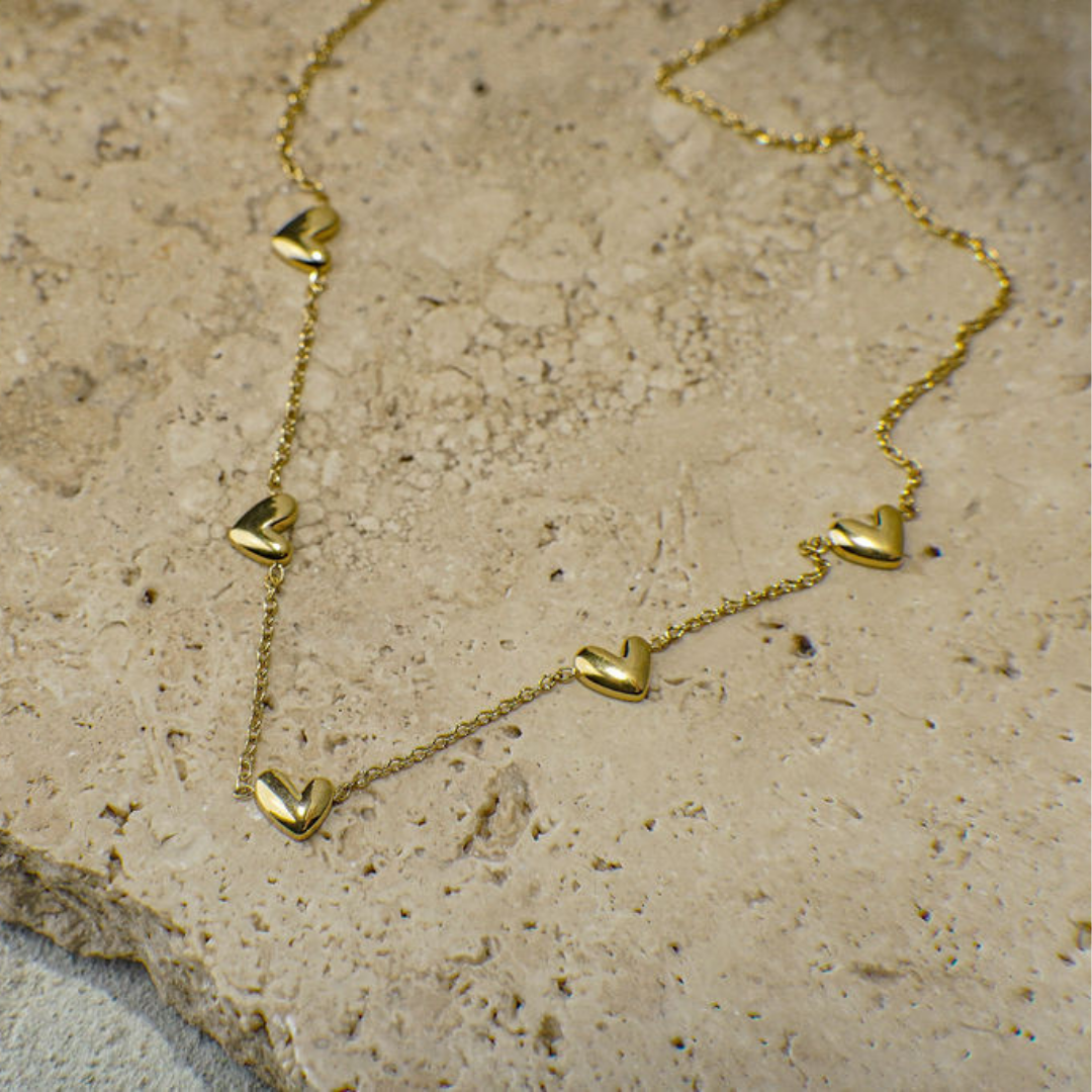 Gold heart-shaped necklace on a textured stone surface