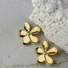 Gold flower-shaped earrings on a textured stone surface