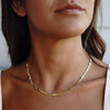 Model wearing gold neckaces with flat circles 