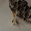 Gold and pearl 'X' shaped ring on a textured surface