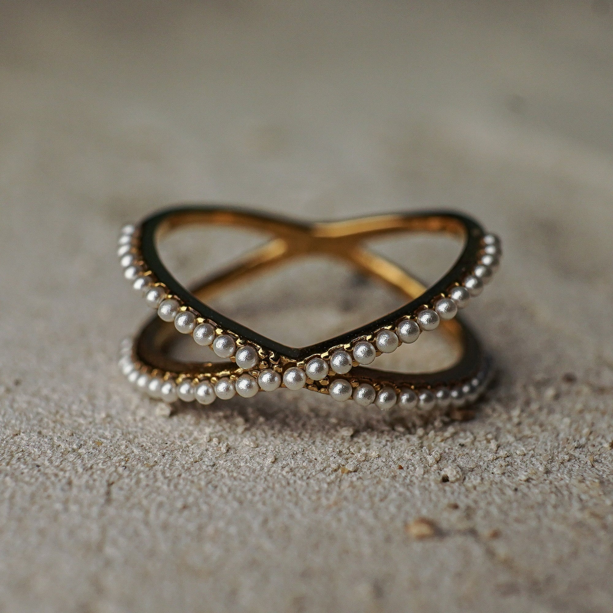 Two interlocking rings with pearl detailing on a textured surface