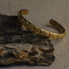 Gold bracelet with intricate designs on a stone surface
