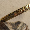 Gold bracelet with intricate designs on a stone surface