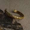 Gold bracelet with intricate designs on a stone surface