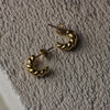 Gold hoop earrings on a textured beige surface