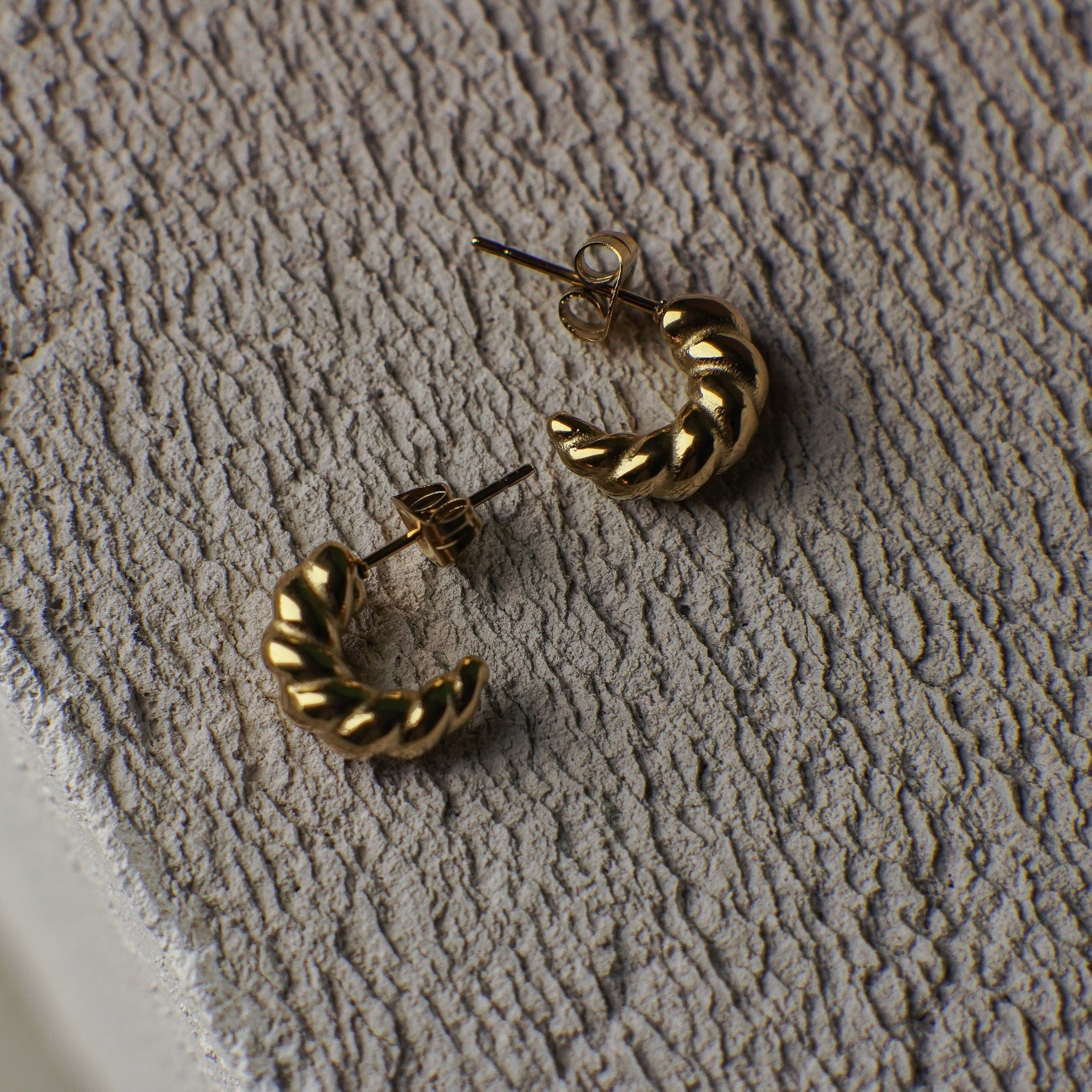 Gold hoop earrings on a textured beige surface