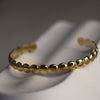 Gold beaded bracelet on a white surface with a dark background