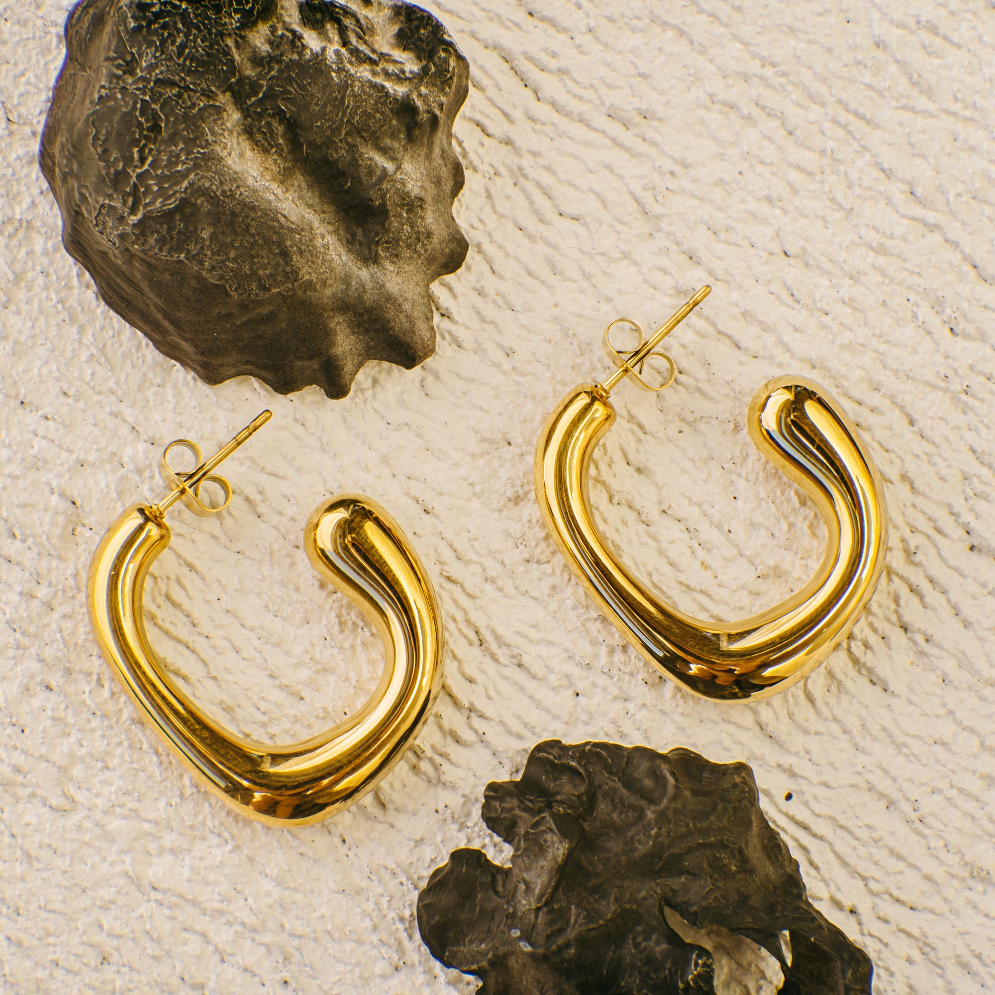 A pair of big gold hoop earrings on a textured surface