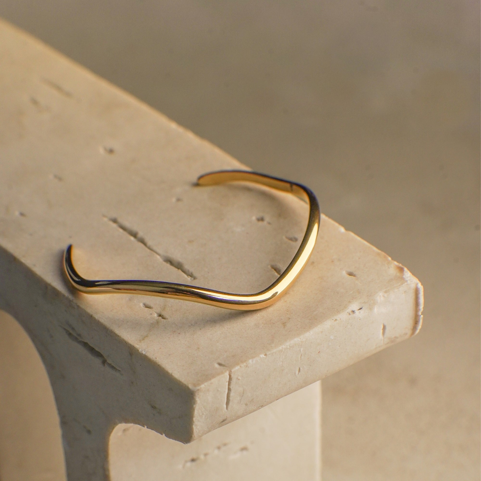 Gold bracelet on a textured stone surface
