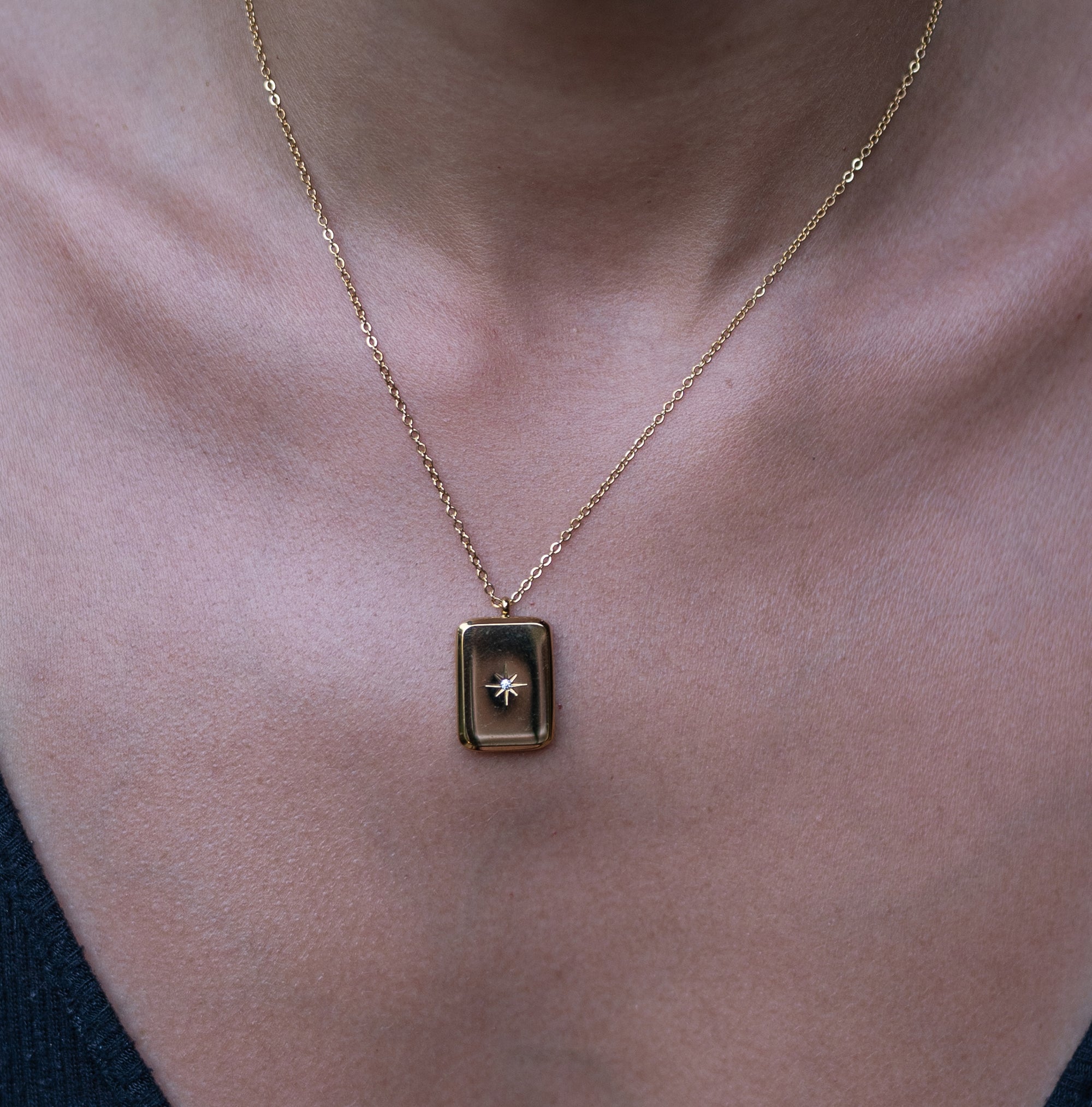 A model wearing a gold necklace with star engraved pendant