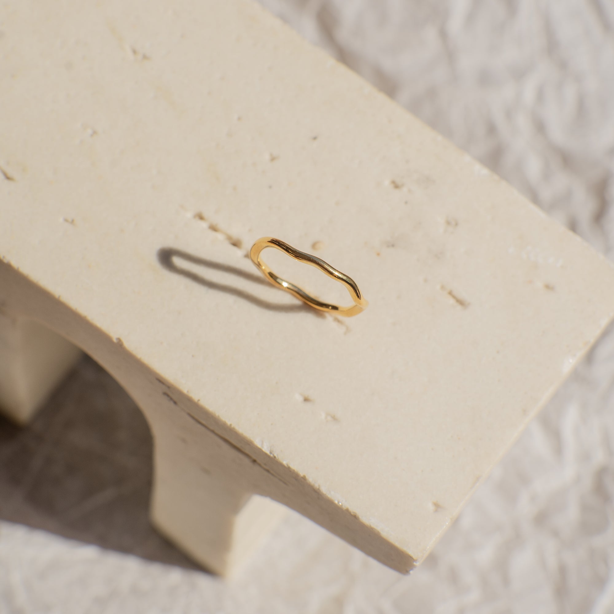 Gold ring on a beige stone surface