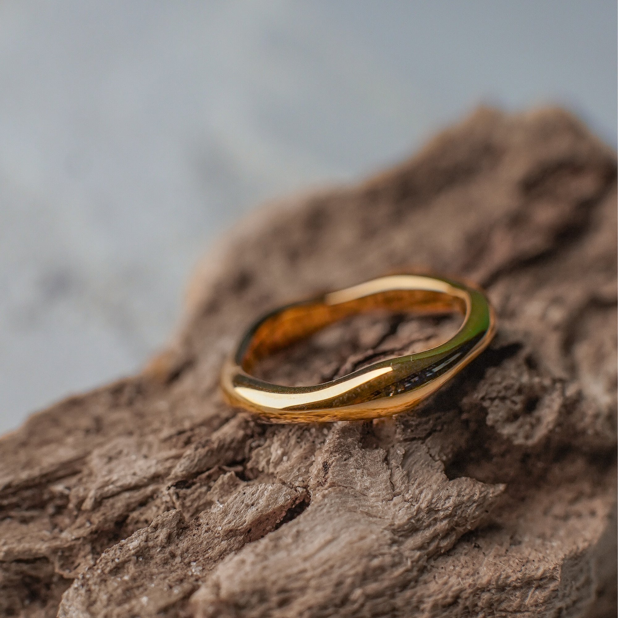 Gold ring on a textured brown surface with a blurred gray background