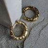 Gold hoop earrings on a textured gray surface