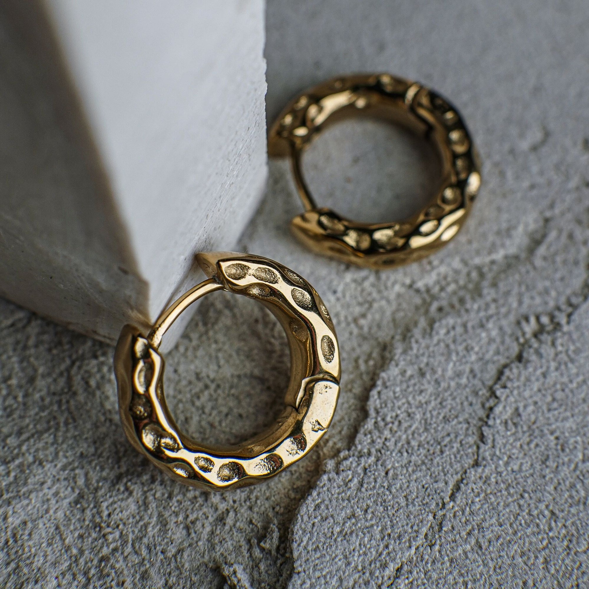 Gold hoop earrings on a textured gray surface