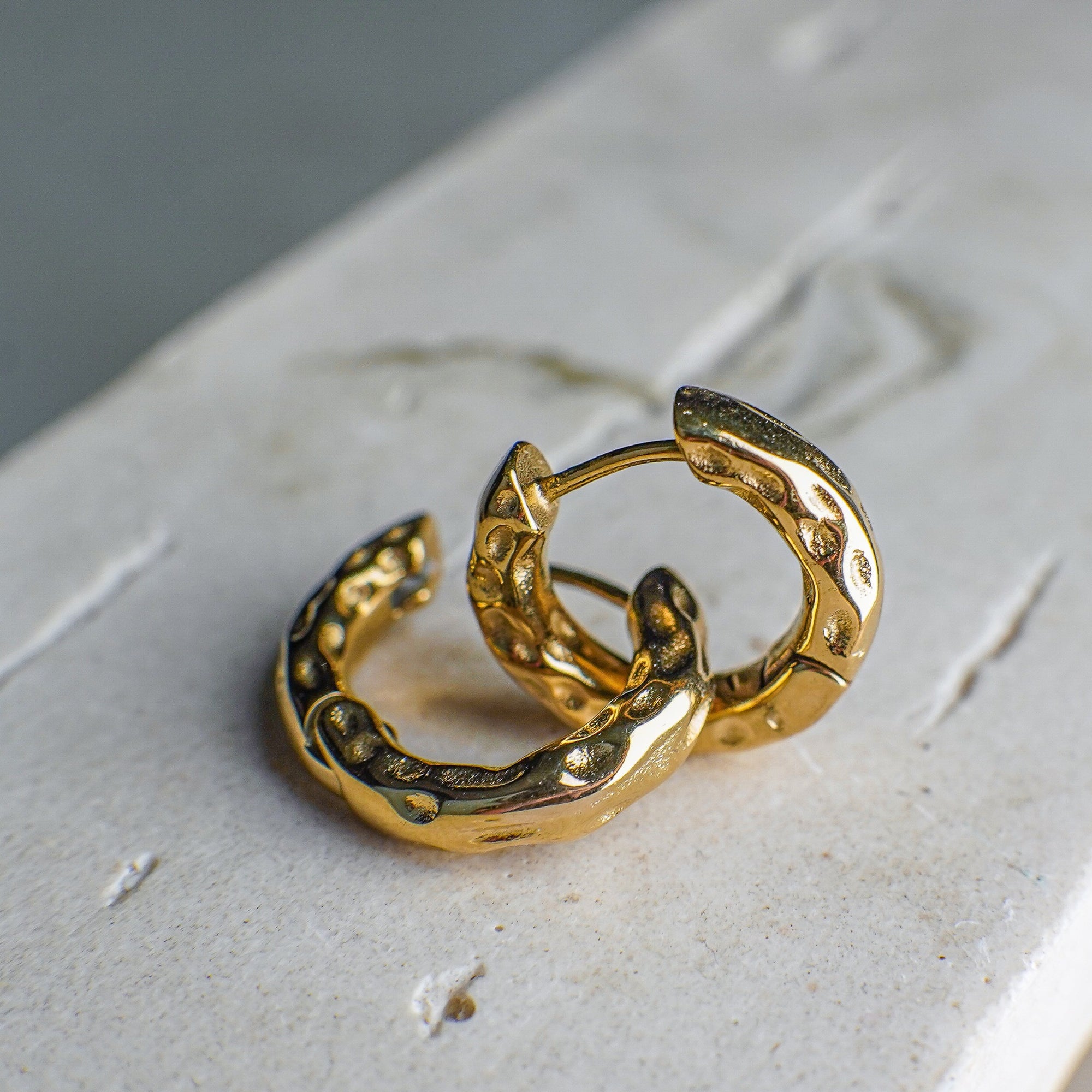 Gold hoop earrings on a textured surface
