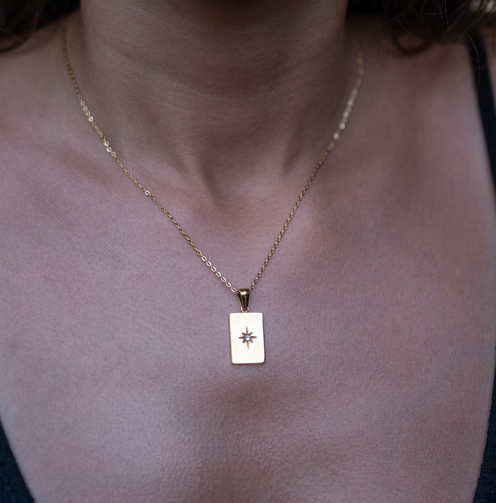 A model wearing a gold necklace with long star pendant