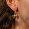 A model wearing a gold heart earring with a little crystal on the center of the star engravement 