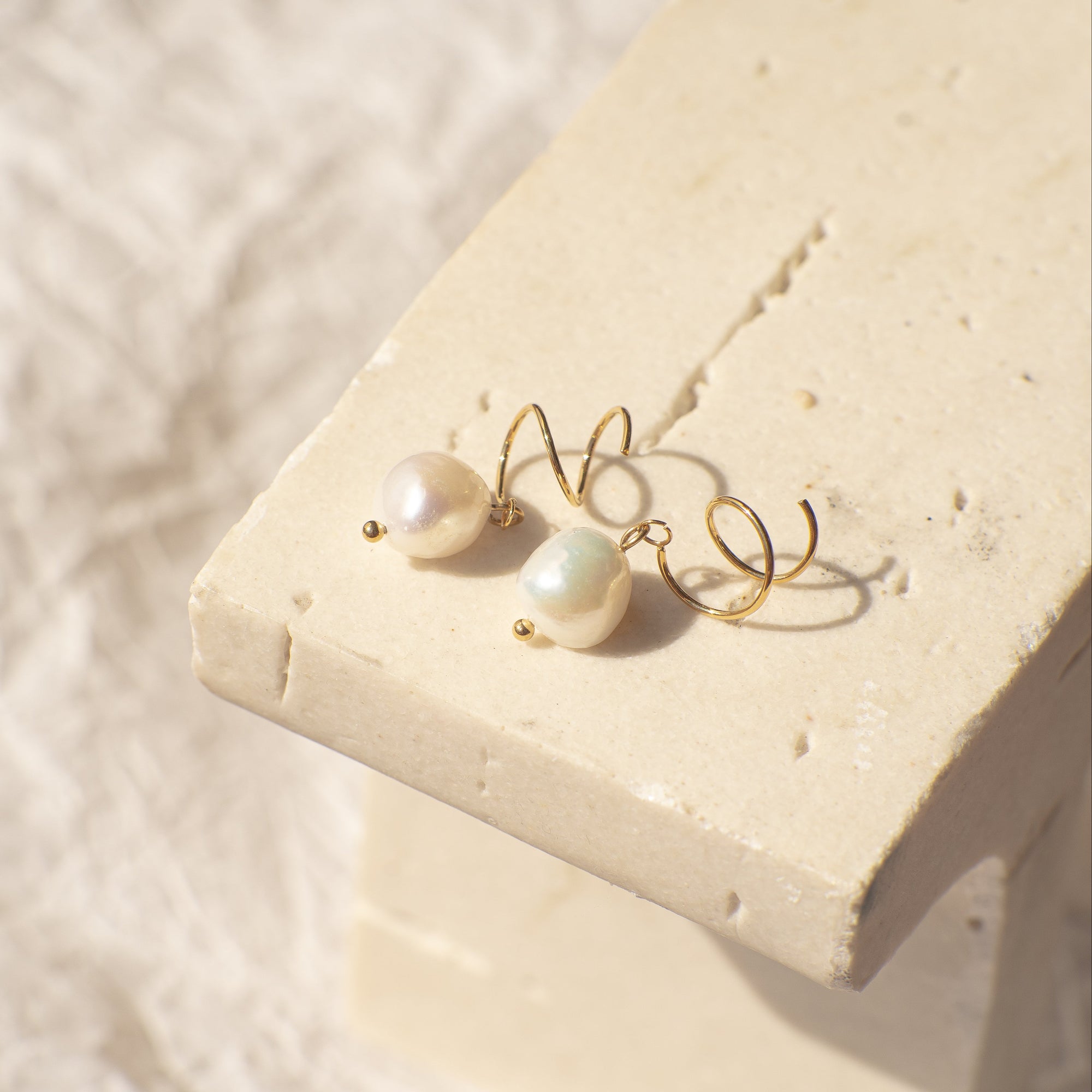 Pearl earrings on a textured beige surface