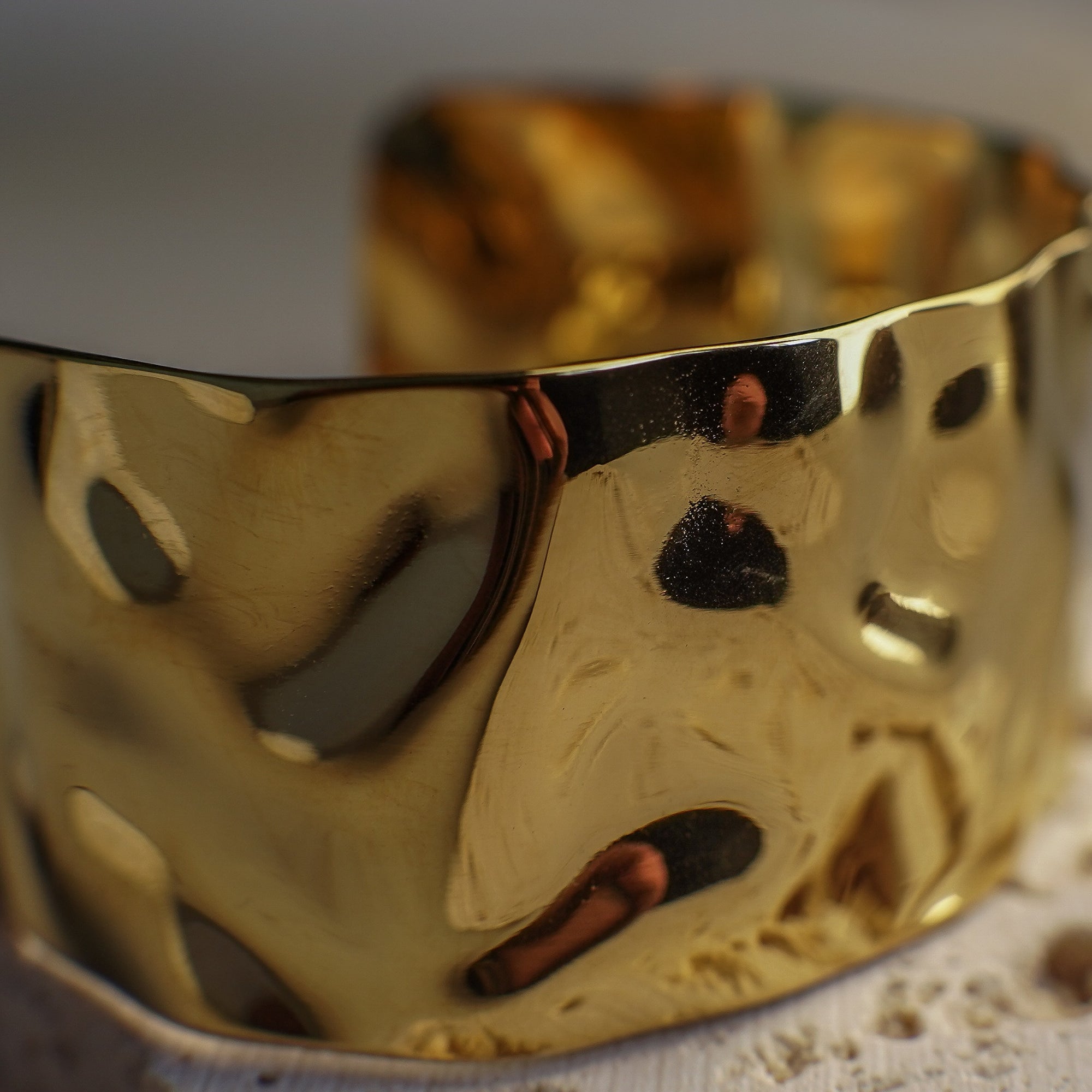 Gold bracelet with textured surface on a neutral background