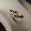 Gold ring with pink gemstones on a textured surface