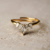 Gold ring with pear-shaped diamonds on a textured surface