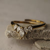 Gold ring with teardrop-shaped diamonds on a textured stone surface