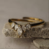 Gold ring with teardrop-shaped diamonds on a textured stone surface