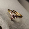 Gold ring with pink gemstones on a textured surface
