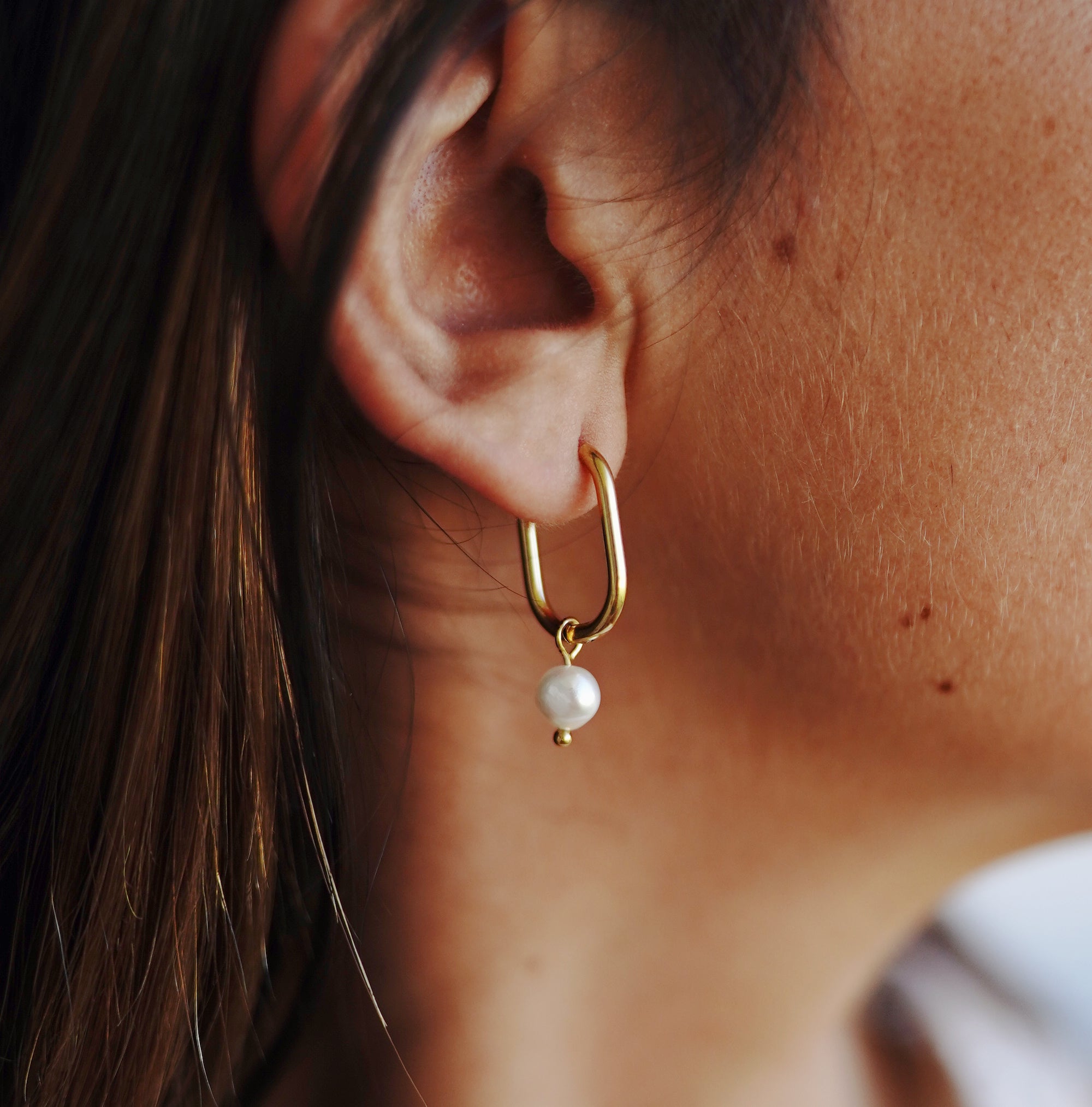 A woman wearing Mara Gold Pearl Earrings