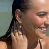 A woman modeling Mara Gold Pearl Earrings paired with other jewelleries