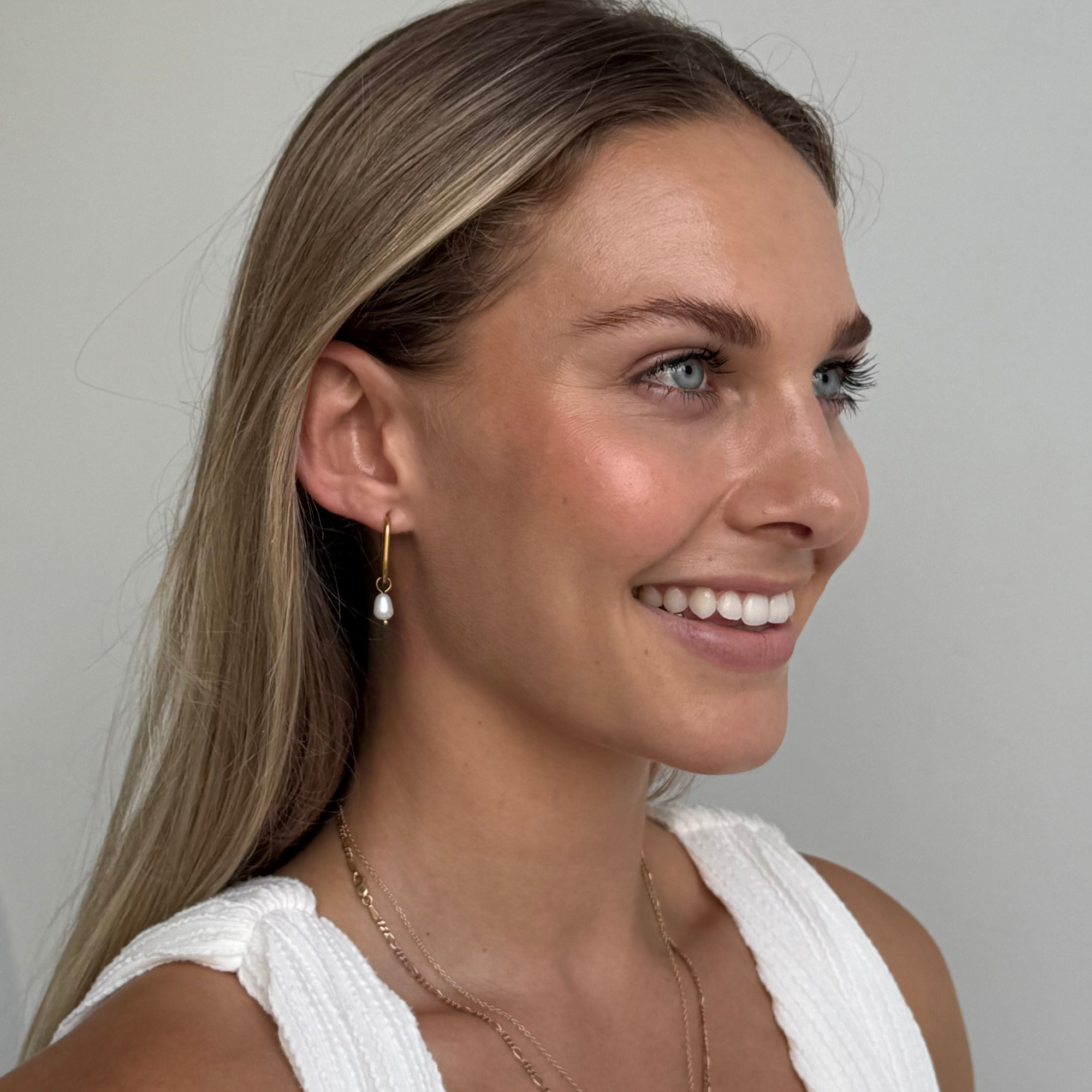 A model wearing Mara Gold Pearl Earrings