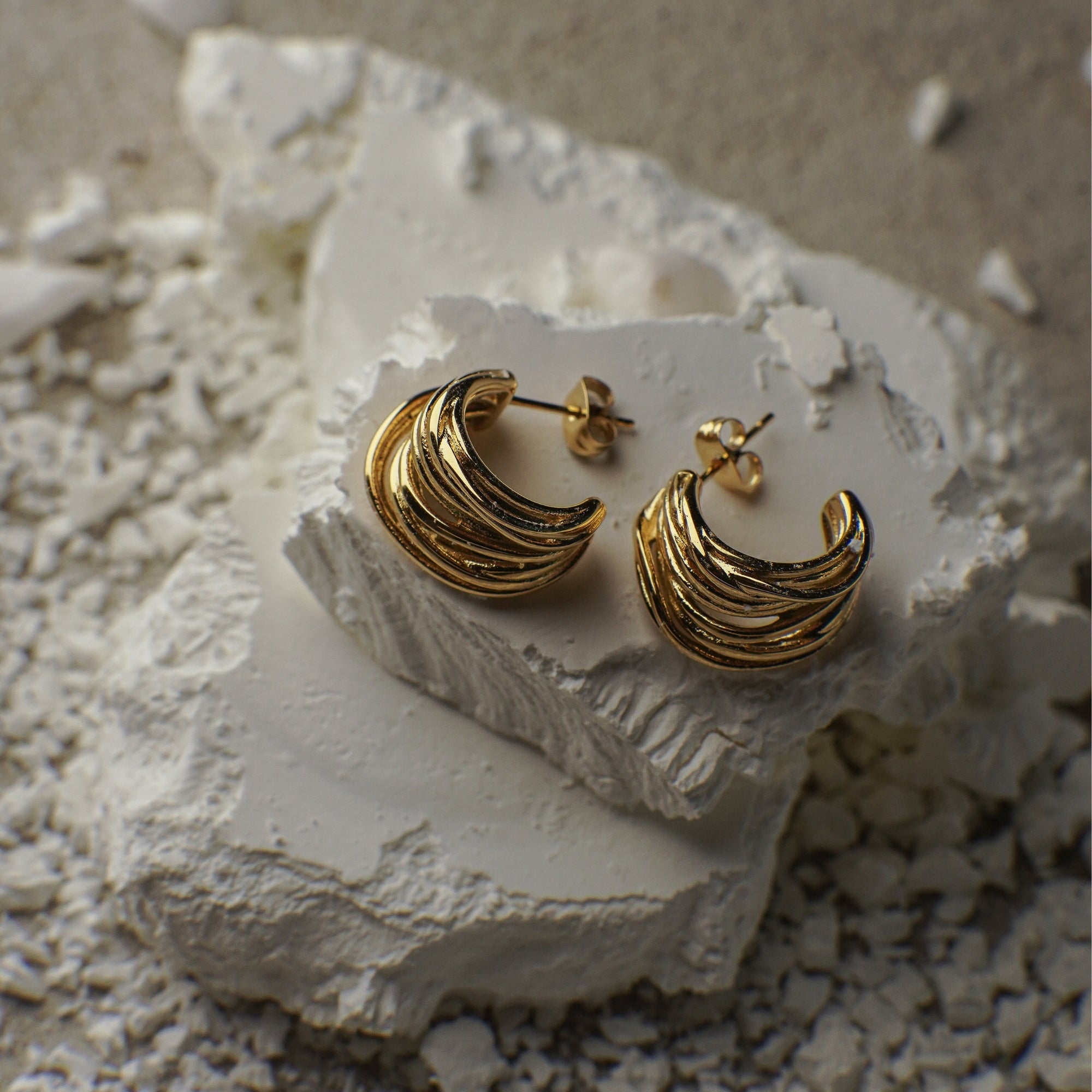 Gold hoop earrings on a textured white surface