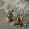 Gold earrings on a textured surface with small stones