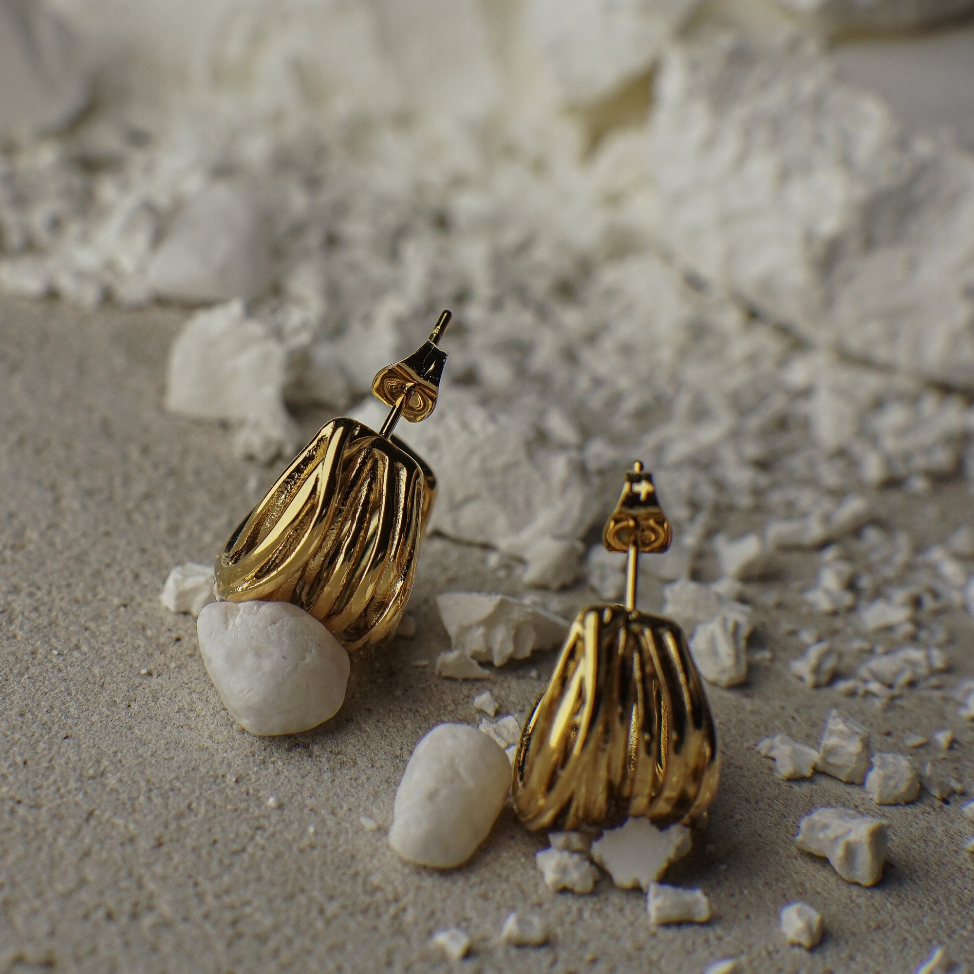 Gold earrings on a textured surface with small stones
