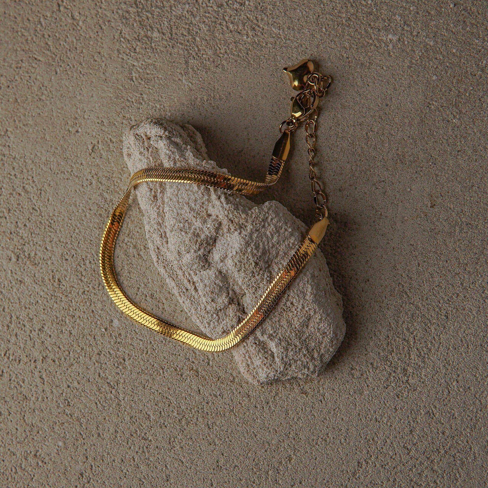 Gold chain bracelet on a textured stone surface