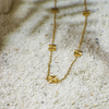 Gold necklace with geometric pendants on a textured white surface