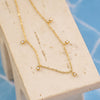 Gold necklace on a white stand with a blue tiled background